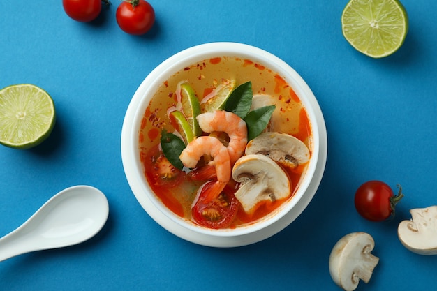 Sabrosa sopa Tom yum sobre fondo azul.