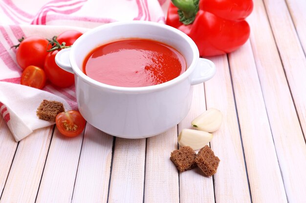 Sabrosa sopa de tomate y verduras en la mesa de madera