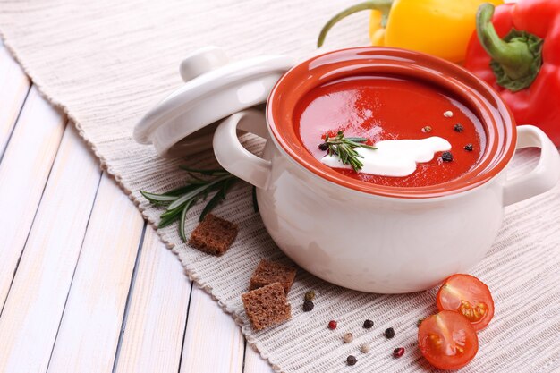 Sabrosa sopa de tomate y verduras en la mesa de madera