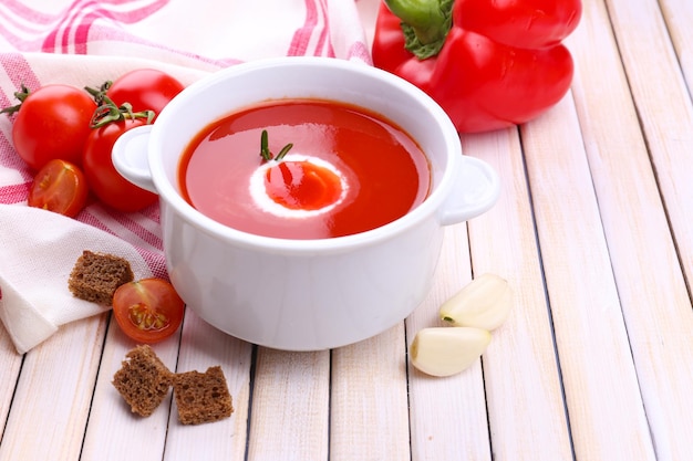 Sabrosa sopa de tomate y verduras en la mesa de madera