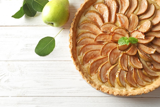 Sabrosa tarta de pera en mesa de madera blanca