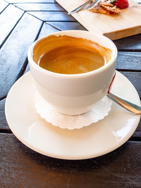 Sabrosa taza blanca de capuchino con arte latte en mesa de madera