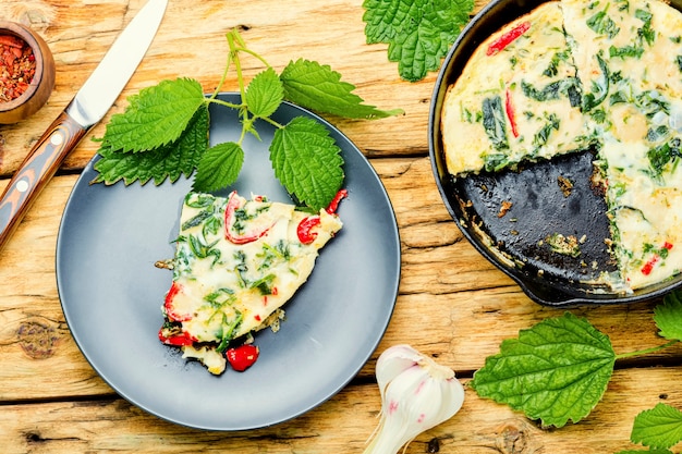 Sabrosa tortilla con hierbas frescas y ortigas en una sartén