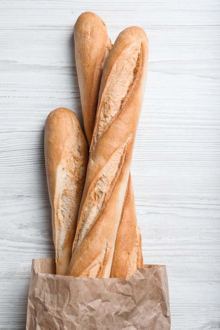 Foto sabrosas baguettes en paquete en la vista superior de la mesa de madera blanca