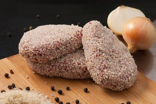 Sabrosas chuletas de cerdo cruda con cebolla en pan rallado