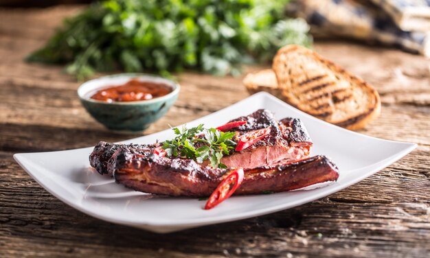 Sabrosas costillas de cerdo a la parrilla con chiles y hierbas de perejil.