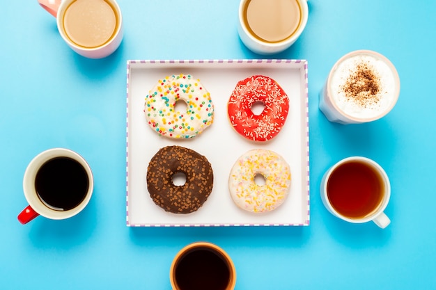 Sabrosas donas y tazas con bebidas calientes, café, capuchino, té