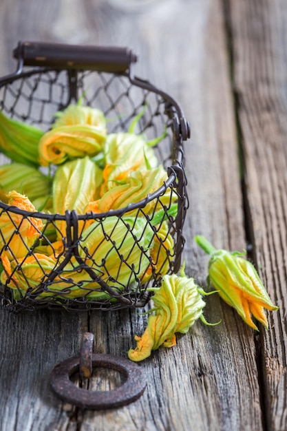 Sabrosas flores de calabacín en una vieja canasta pequeña