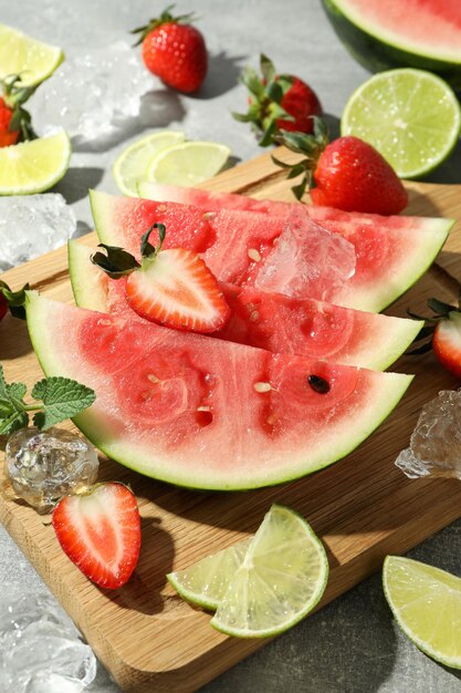 Sabrosas frutas frescas con hielo en una mesa con textura gris