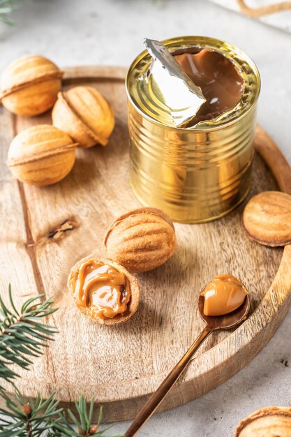 Sabrosas galletas en forma de nuez con leche condensada hervida en tablero de madera con ramas de abeto Proceso