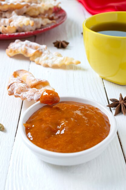 Sabrosas galletas fritas crujientes en azúcar en polvo con té y mermelada en el desayuno