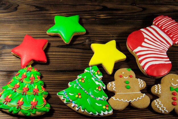 Sabrosas galletas de jengibre de Navidad festivas en forma de árbol de Navidad, hombre de jengibre, estrella y calcetín de Navidad en la mesa de madera. Vista superior