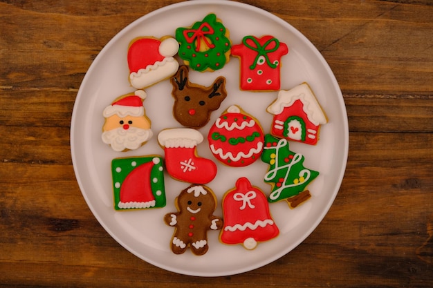 sabrosas galletas de Navidad en un plato blanco sobre una mesa de madera. Deliciosas y coloridas galletas navideñas. Navidad