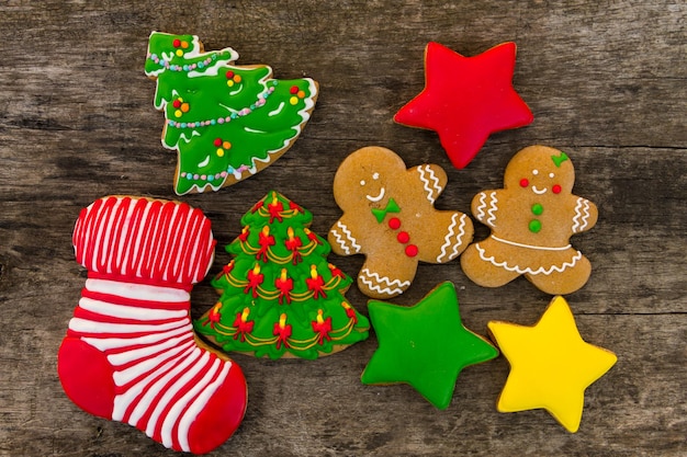 Sabrosas galletas navideñas festivas en forma de árbol de Navidad, hombre de jengibre, estrella y calcetín de Navidad en la mesa de madera rústica. Vista superior