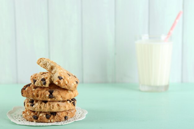 Sabrosas galletas y vaso de leche sobre fondo de madera de color