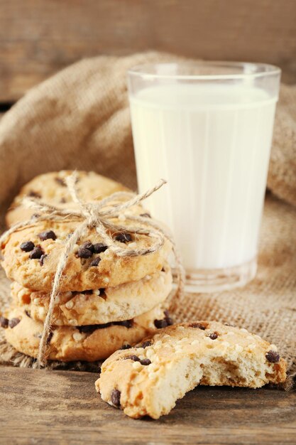 Sabrosas galletas y vaso de leche sobre fondo de madera rústico