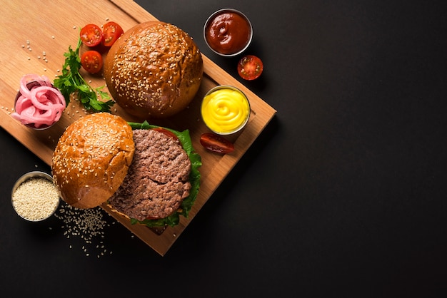 Sabrosas hamburguesas de carne sobre una tabla de madera con salsas