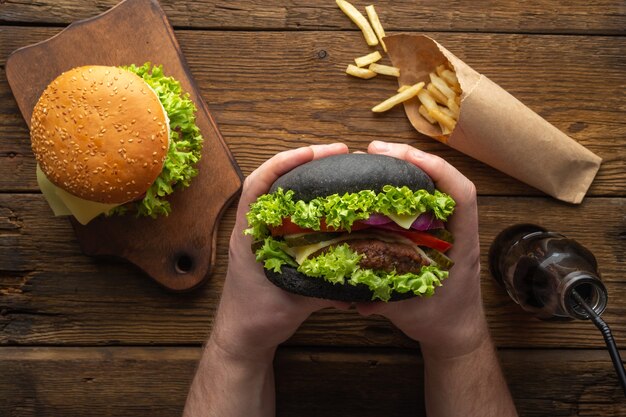 Sabrosas hamburguesas frescas con papas fritas, bebida en la vista superior de la mesa de madera.