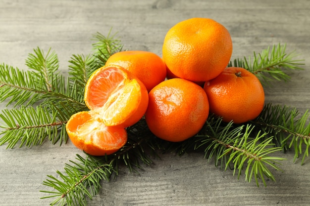 Sabrosas mandarinas y ramas de abeto en mesa con textura gris