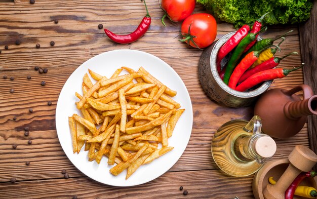 Sabrosas papas fritas en tabla de cortar, mesa de madera