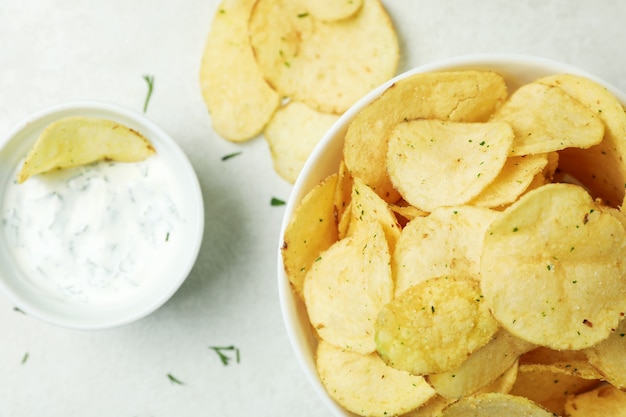 Sabrosas patatas fritas y salsa sobre superficie con textura blanca