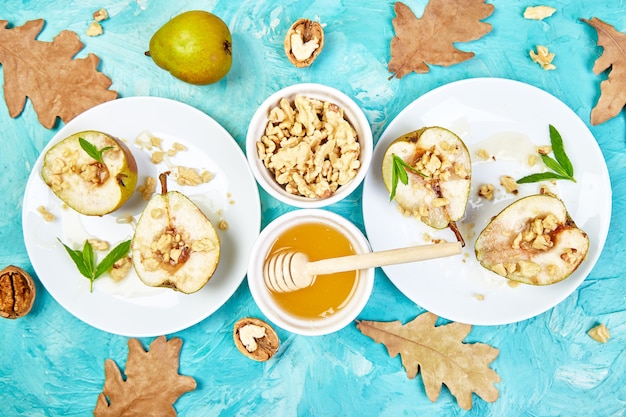 Sabrosas peras asadas con miel y nueces sobre tabla de fondo azul.