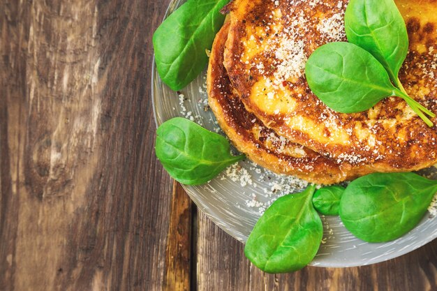 Sabrosas tostadas francesas con queso parmesano y espinacas sobre fondo de madera rústica. Vista superior.