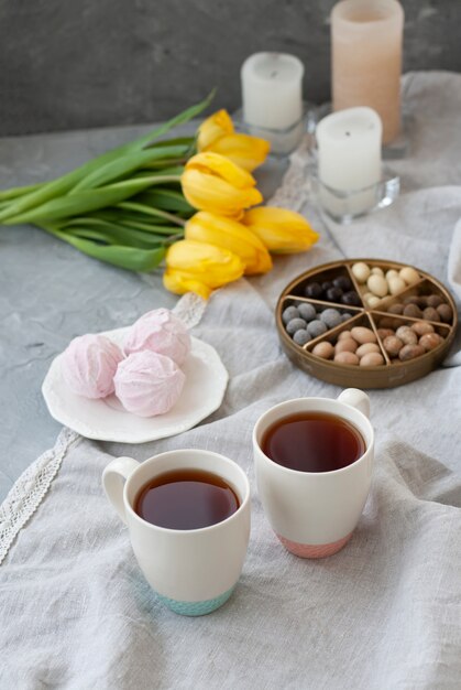 Un sabroso aperitivo: dos tazas de té, un plato de zephyr y una caja de dulces.