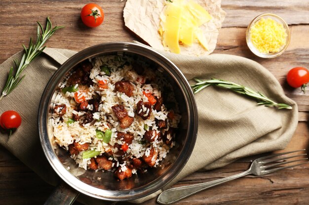 Sabroso arroz en sartén sobre mesa de madera