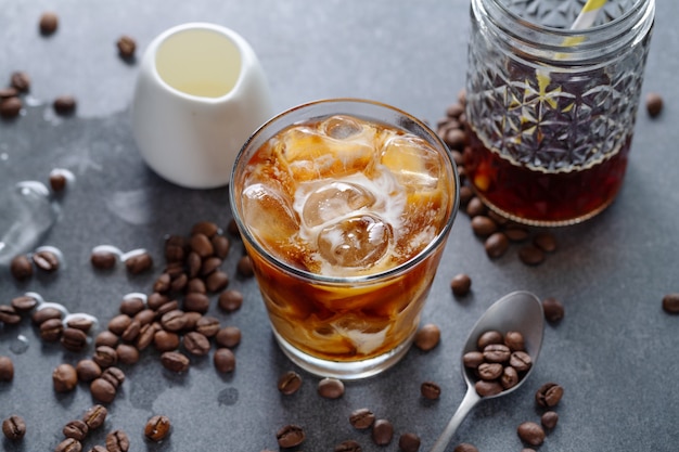 Sabroso café helado refrescante con cubitos de hielo en vasos sobre fondo brillante. De cerca