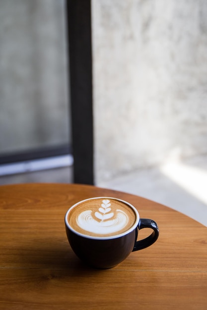 Sabroso capuchino con hermoso arte latte en una mesa de madera en el café