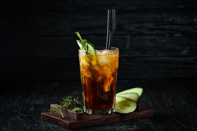 Sabroso cóctel alcohólico Cola whisky pepino y hielo Sobre un fondo de madera Vista superior