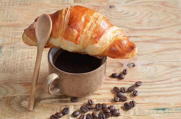 Sabroso croissant y taza de café en el fondo de madera vieja