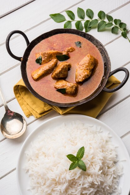 Sabroso curry de pescado servido con arroz basmati cocido blanco con hojas de curry en el fondo, comida india costera favorita
