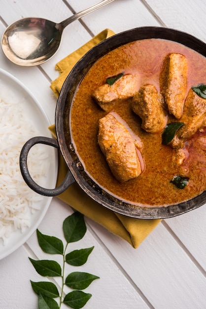 Sabroso curry de pescado servido con arroz basmati cocido blanco con hojas de curry en el fondo, comida india costera favorita