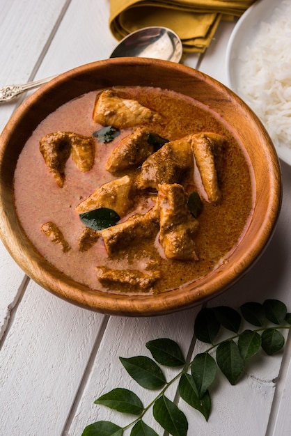 Sabroso curry de pescado servido con arroz basmati cocido blanco con hojas de curry en el fondo, comida india costera favorita