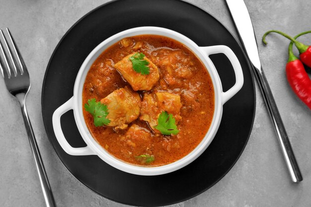 Sabroso curry de pollo en plato de sopa sobre fondo gris