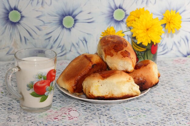 Sabroso desayuno Pasteles de manzana y leche fresca son una reserva de energía para el día Pasteles y flores amarillas en la cocina de la abuela primer plano