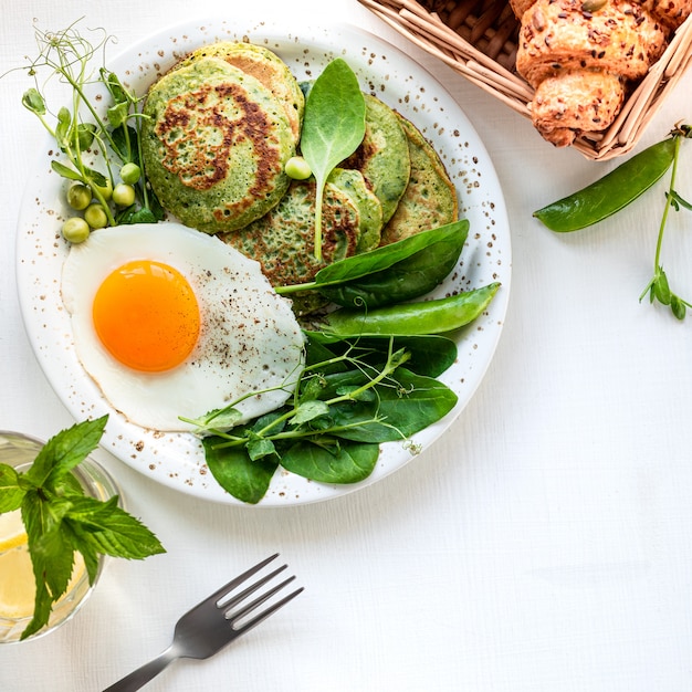Sabroso desayuno saludable. Panqueques verdes con espinacas, huevo y guisantes jóvenes. vista superior. copia espacio
