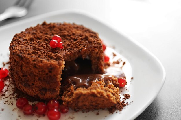 Sabroso fondant de chocolate con grosella roja en primer plano de placa blanca