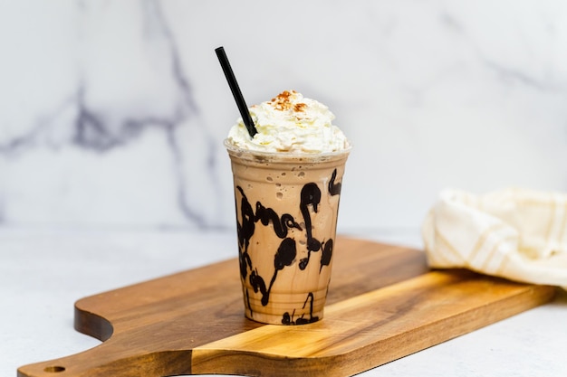 Sabroso Frappuccino fresco con crema servido en la tabla de madera