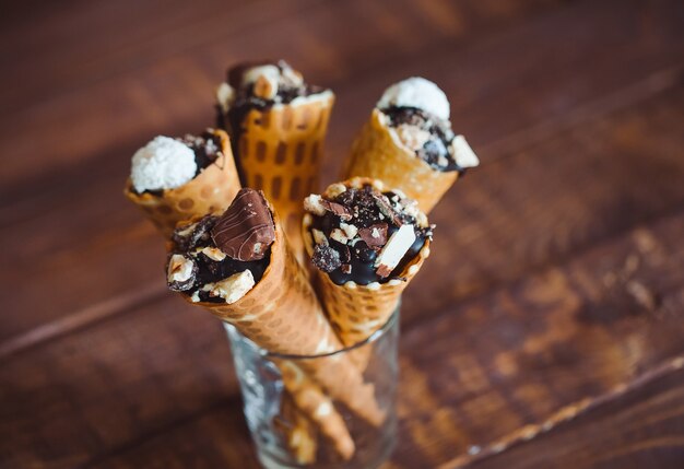 Sabroso helado de chocolate en cono de galleta sobre fondo de madera marrón