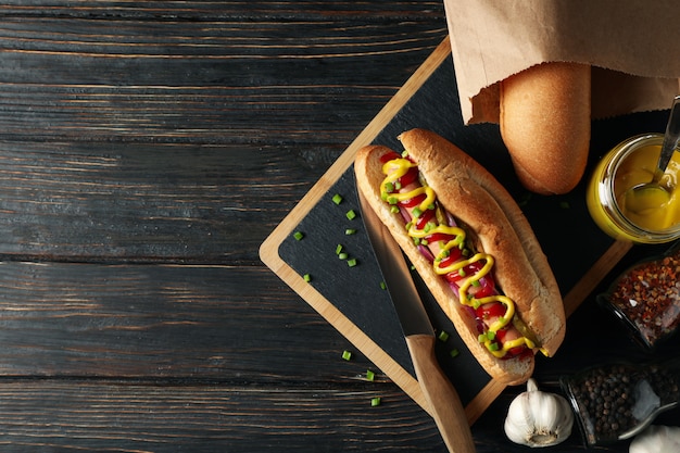 Sabroso hot dog e ingredientes en madera