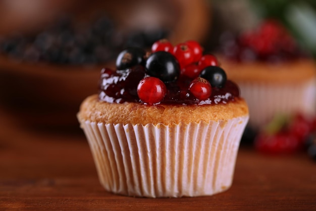 Sabroso muffin con bayas en mesa de madera