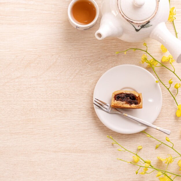 Sabroso pastel de luna para el festival MidAutumn en una mesa de madera brillante concepto de té festivo decorado con flores amarillas vista superior plana