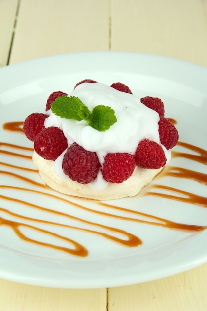 Sabroso pastel de merengue con frutos rojos en mesa de madera