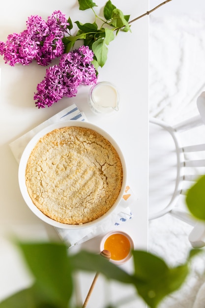 Sabroso pastel de queso casero en un plato blanco sobre una mesa con lilas