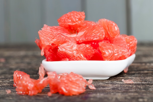 Sabroso pomelo rojo jugoso sobre una tabla de madera, frutos cítricos útiles