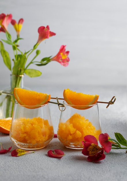 Foto sabroso postre de granizado con bodegones de naranja y flores.