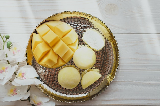 Sabroso postre Mochi con fruta de mango sobre fondo de madera